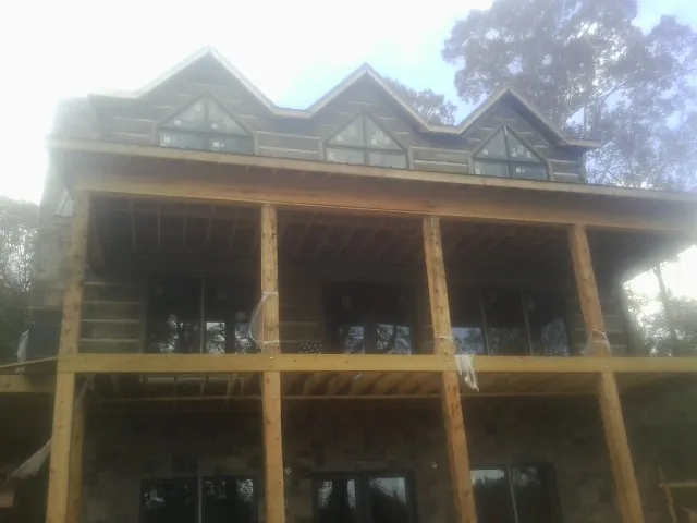 Dormers and porch framing on a large log home under construction — Roof Coating work by our crew in Saint John
